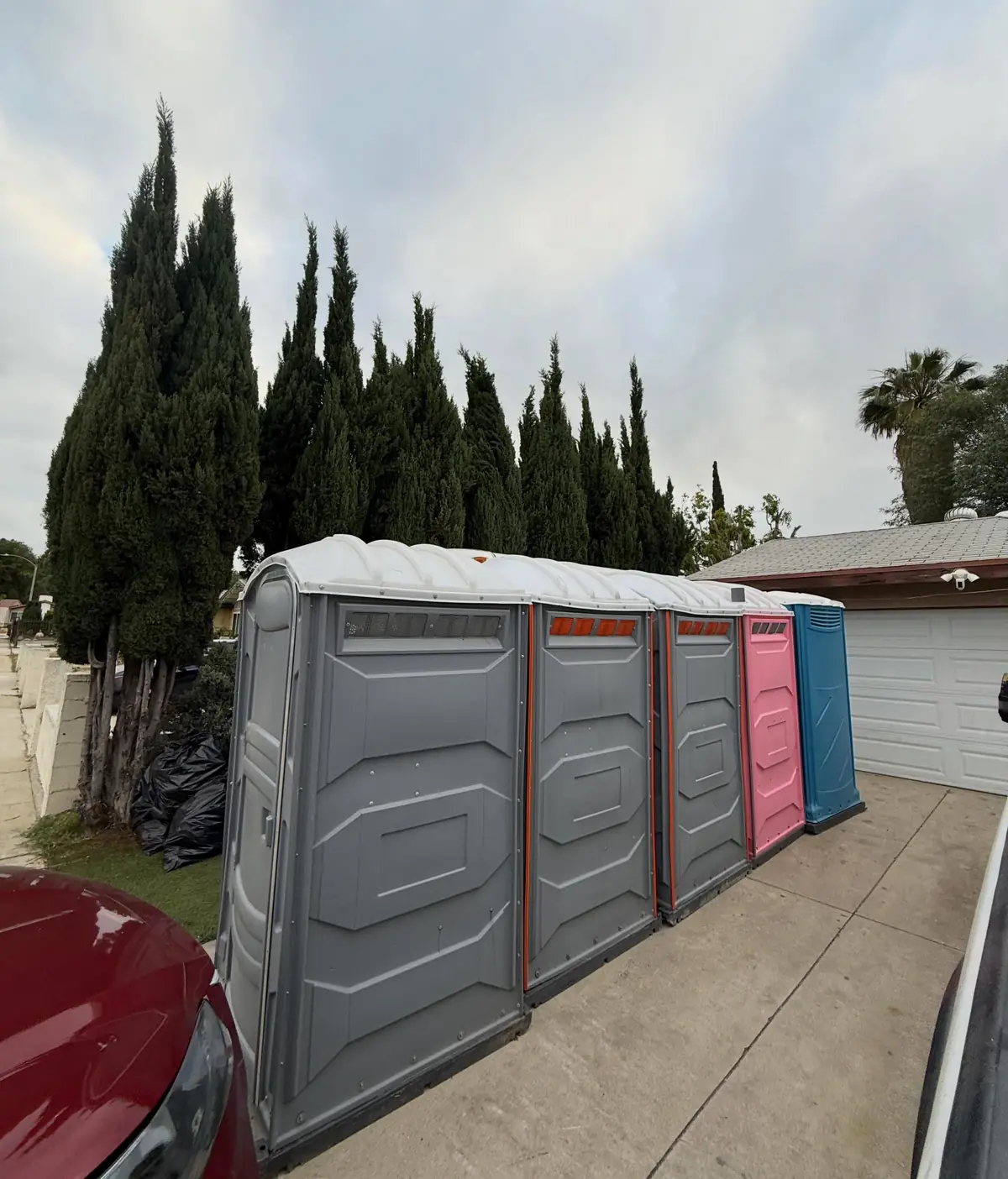 Row of grey porta potties lined up along a driveway