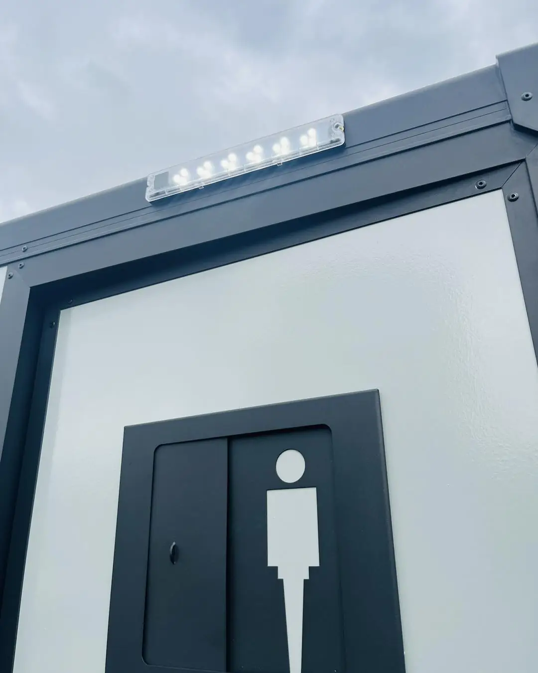 Restroom trailer entry door with a sign and light above it