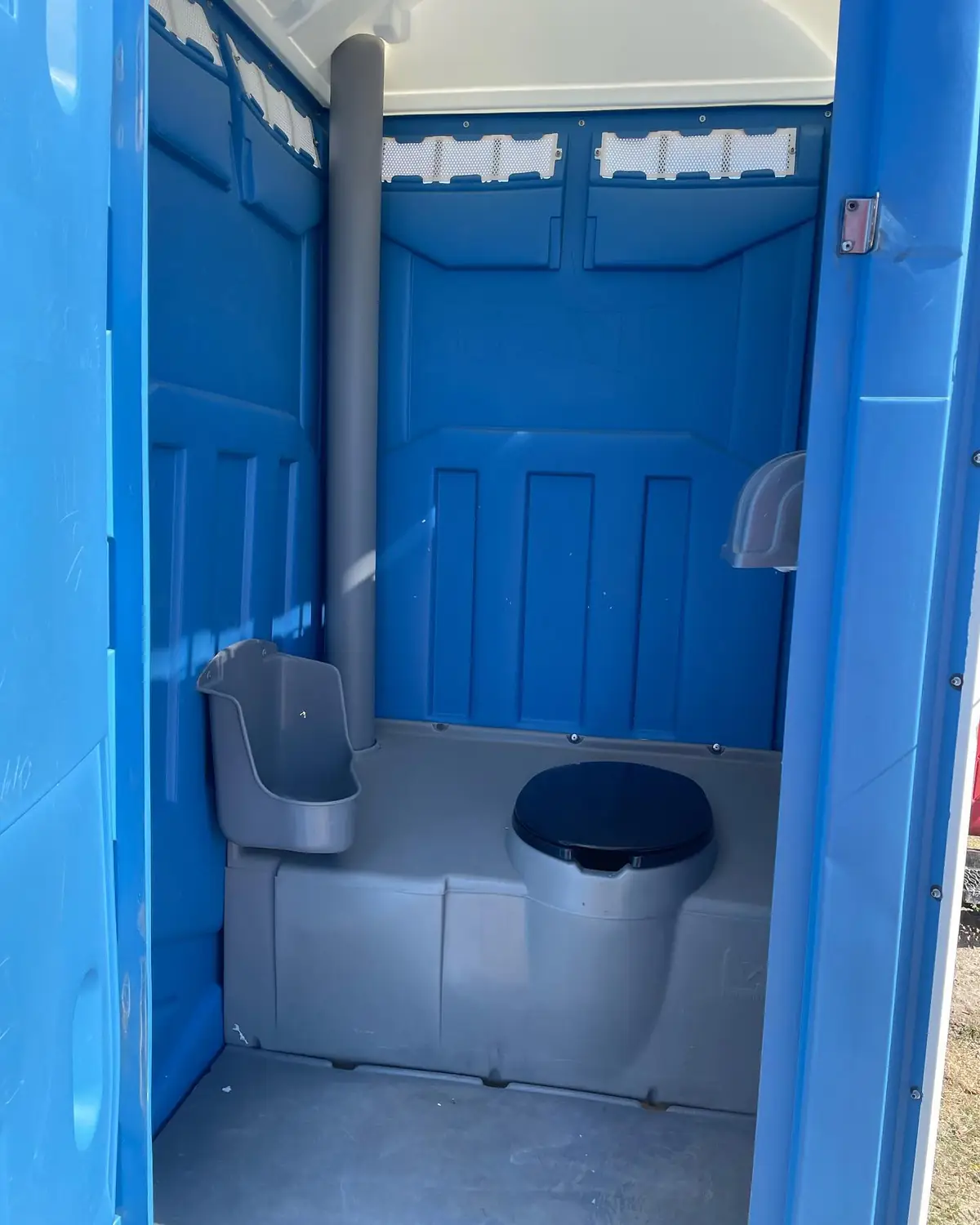 Inside a standard porta potty with seat, urinal and paper holder