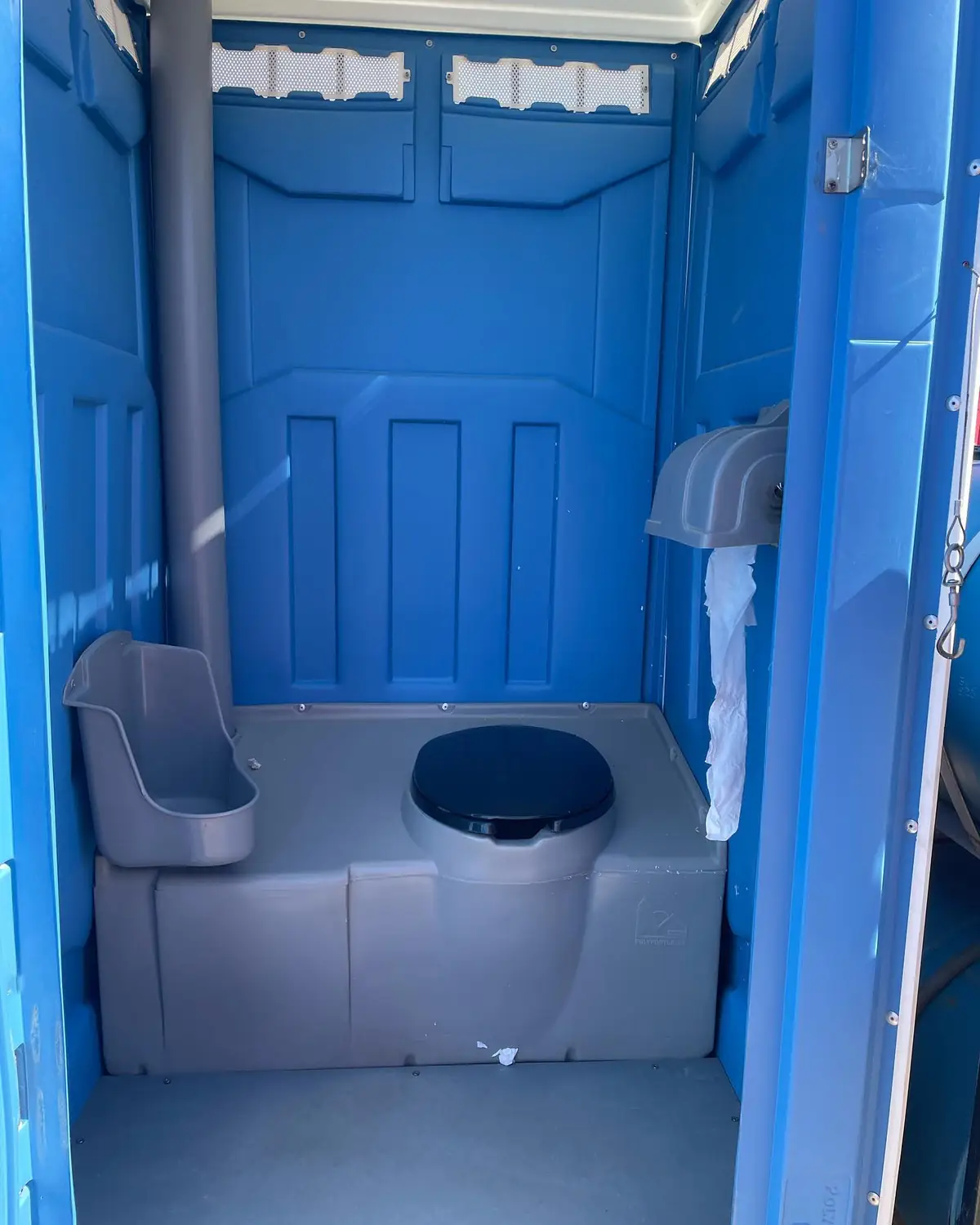 Interior of a standard porta potty showing the toilet paper dispenser