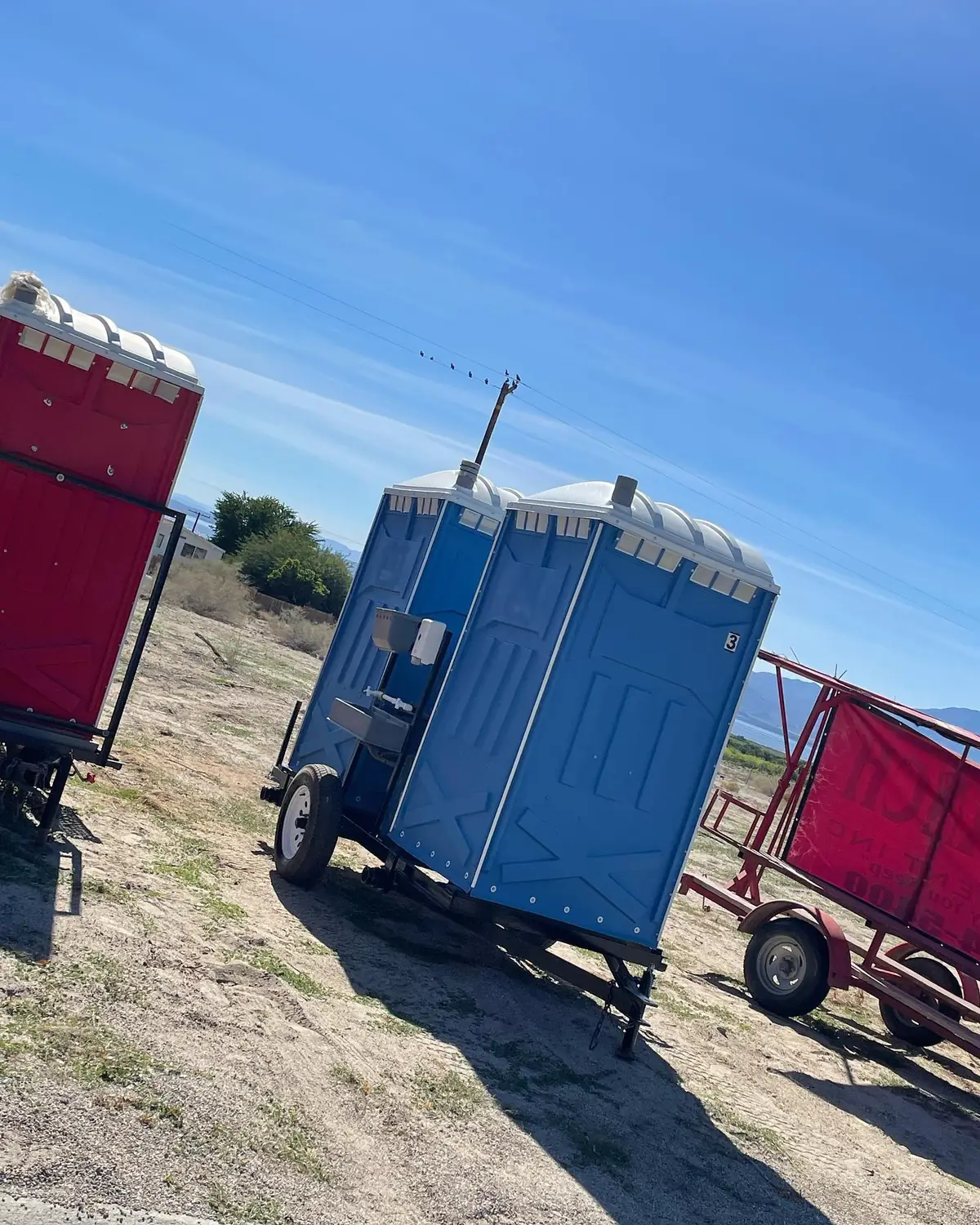 Blue porta potties loaded on a trailer in an open field